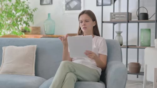 Young Woman Shocked by Business Report Loss while Reading at Home