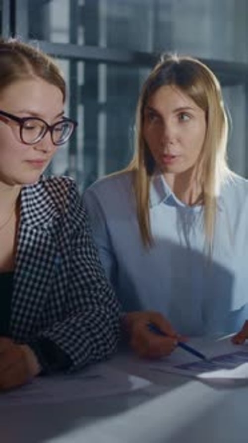 Konzentrierte weibliche Kollegen, die in einem hellen, modernen Büro an Papierkram und Datenanalyse zusammenarbeiten