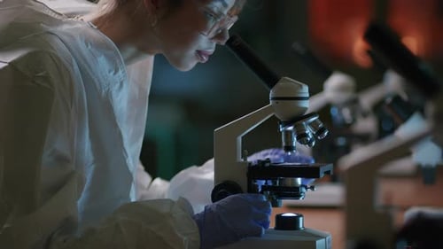 Young Scientist Works with Microscope in Dark Laboratory