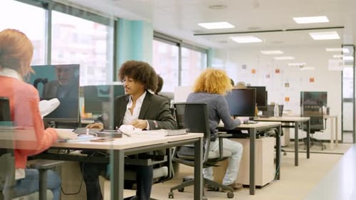 Collègues multiethniques travaillant avec des ordinateurs sur des bureaux