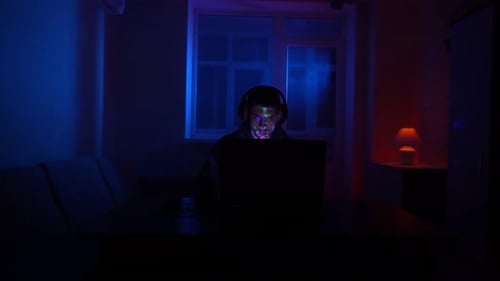 Person using Laptop with Headphones in Dark Room