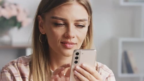 Blonde Woman Smiles Using Smartphone Indoors