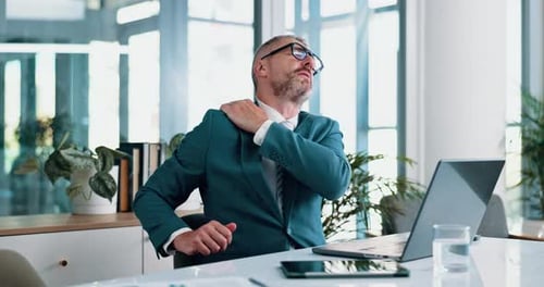 Mature, businessman and shoulder pain with laptop for stress, pressure or muscle tension at office
