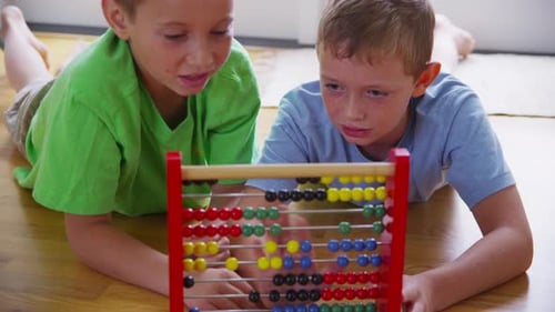 Dos niños pequeños que aprenden matemáticas juguetonamente con un ábaco en casa filmados en una epopeya roja