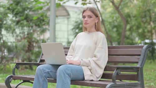 Woman Using Laptop on Park Bench