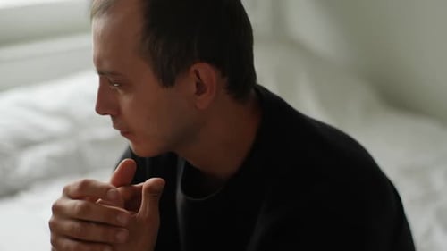 Distressed Man Sitting on Bed During Argument