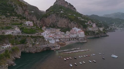 Aerial Slide and Pan Shot of Buildings in Small Old Town Squeezing Between High Rock Cliffs