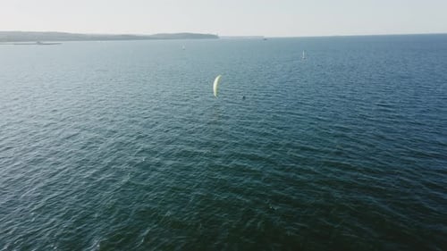 Kitesurfer Glides on Ocean Under Bright Kite