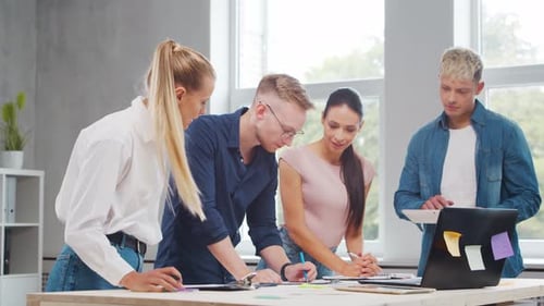 Team of Young Startupers is Working at the Table in the Office Discussing the Strategy and