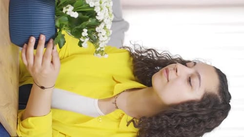 Young Woman Looking at Potted White Flower