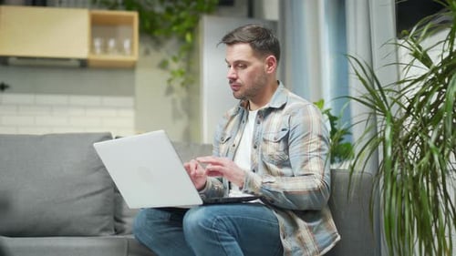 Handsome bearded young man remote meeting via webcam works using laptop computer. Caucasian male