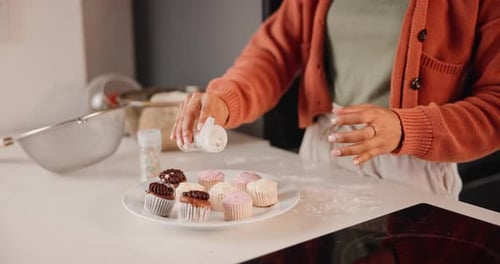 Woman Sprinkles Cupcakes with White Sprinkles