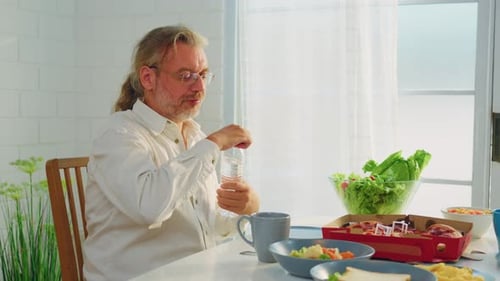Adult Man Pours Water at Lunch Table