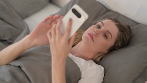 Woman Uses Smartphone in Bed, Close Up