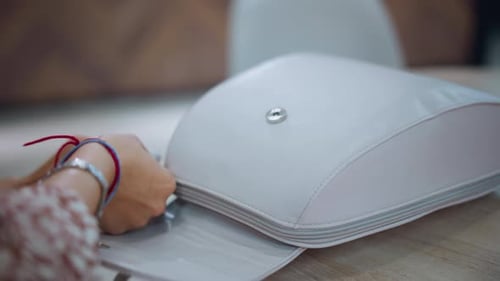 CloseUp of Hands Opening Stylish White Bag on Table