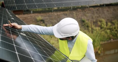 Engineer Man Checking Solar Panel at Photovoltaic Power Station Outdoors