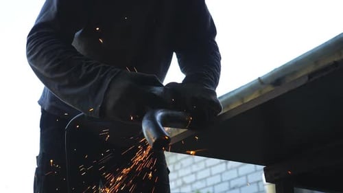 Low View on Unrecognizable Repairman or Mechanic Grinding Iron Detail Using Circular Saw