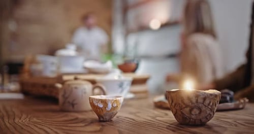 Ancient Bowl Stands on Wooden Table Against People in Cafe