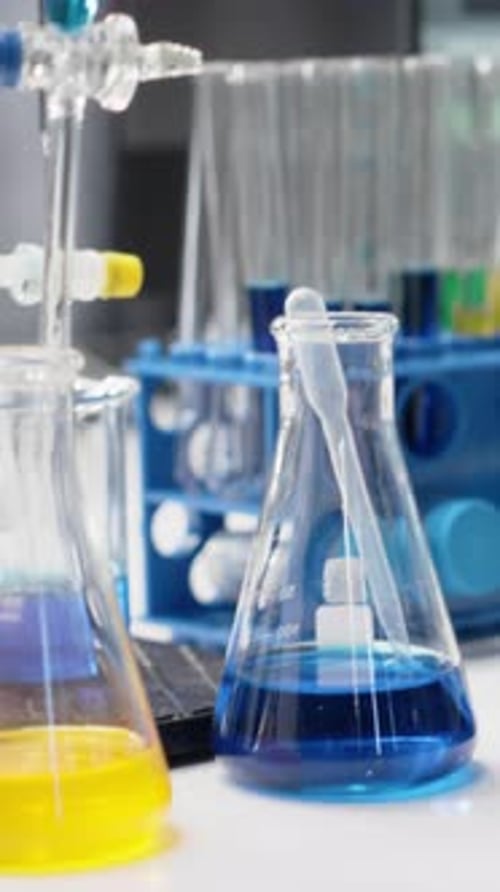 Vertical Video Close Up of Colorful Chemical Solutions Inside Scientific Flasks