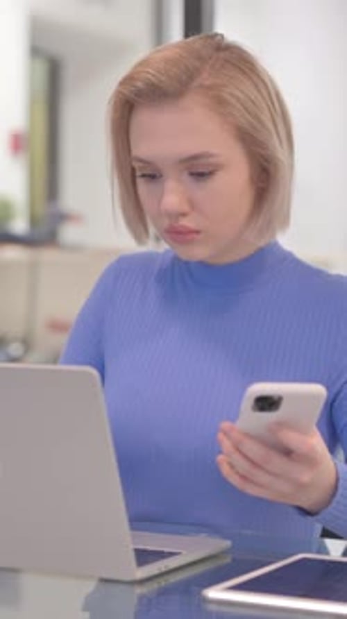 Woman Using Laptop and Smartphone at Table