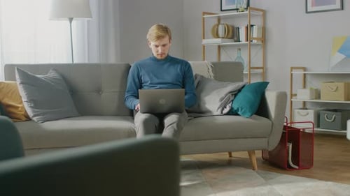 Young Man Using Laptop on Sofa at Home