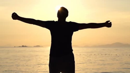 Man stretches arms in golden sunset slow motion on beautiful exotic beach