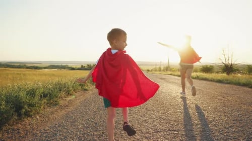 Carefree Children Play Superheroes Wear Red Cloaks Run Along Rural Road on Nature with Spreading
