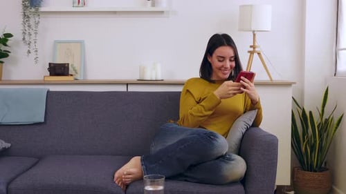 Smiling Woman Using Cellphone Relaxing on Couch
