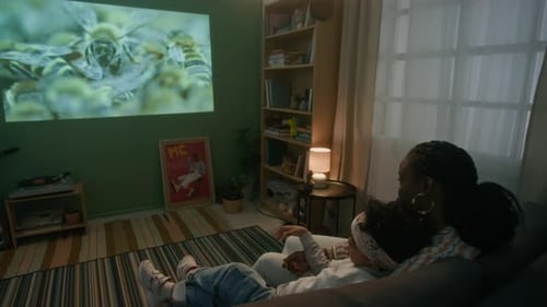Back View of Woman and Her Son Watching Film about Insects Projected on Wall