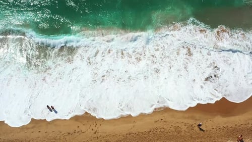 Aerial View of Ocean Waves Rolling Onto Sandy Shore