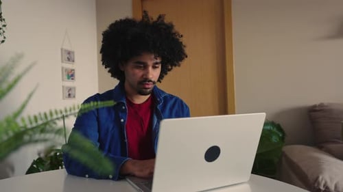 Young Freelancer with Afro Hair Typing on Laptop at Home Office