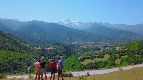 Happy people are travelers, standing on mountain and looking into distance at mountains