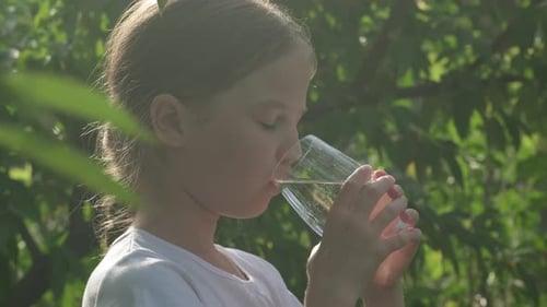 Girl Drinks Refreshing Water Outdoors on Sunny Day