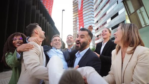 Enthusiastic Colleagues Celebrate Success by Lifting Colleague