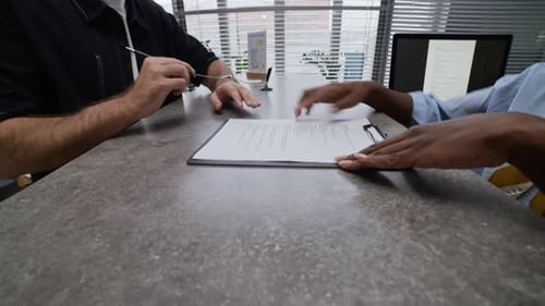 Manager Giving Questionnaire to Man Filling out It in Bank Office