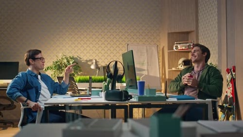 Two Young Men Work at Desk and Laugh