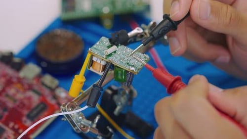 Un ingeniero informático con un probador inspecciona de cerca la placa base