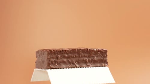 A chocolate bar lies on white paper.