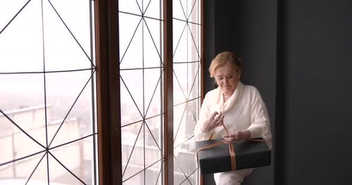 Woman Receiving a Birthday Present by the Window