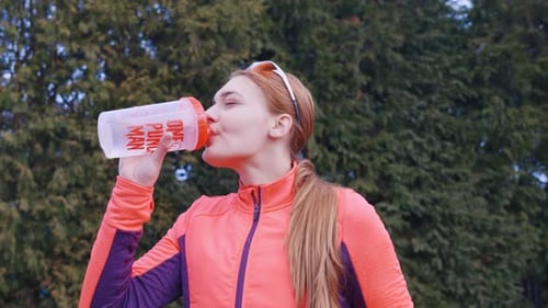 Woman Drinks Water After Exercise in the Park