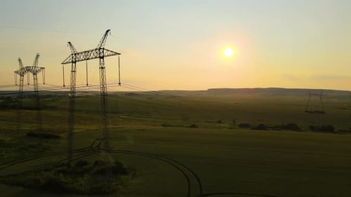 Electrical Towers Stand in Field at Sunset