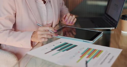 Woman Notes on Bar Graph at Desk with Tablet