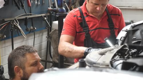 Profile of Two Mechanics Works with Car at Garage Portraits of Repairmans Fixing Vehicle at Workshop
