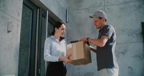 Businesswoman Receiving Her Package From Postal Service Worker Signing POD on Tablet Computer