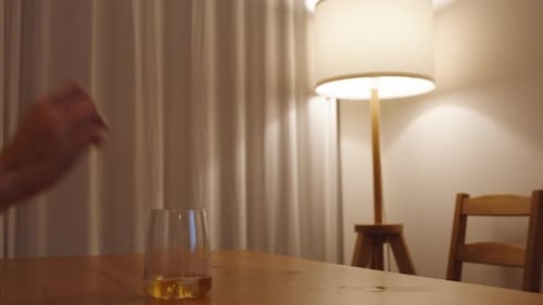 Hand Reaching for Glass of Alcohol with Ice