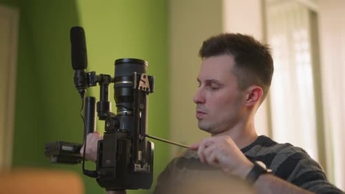 TV Technician Focusing on Camera Setup in Indoor Studio with Green Wall