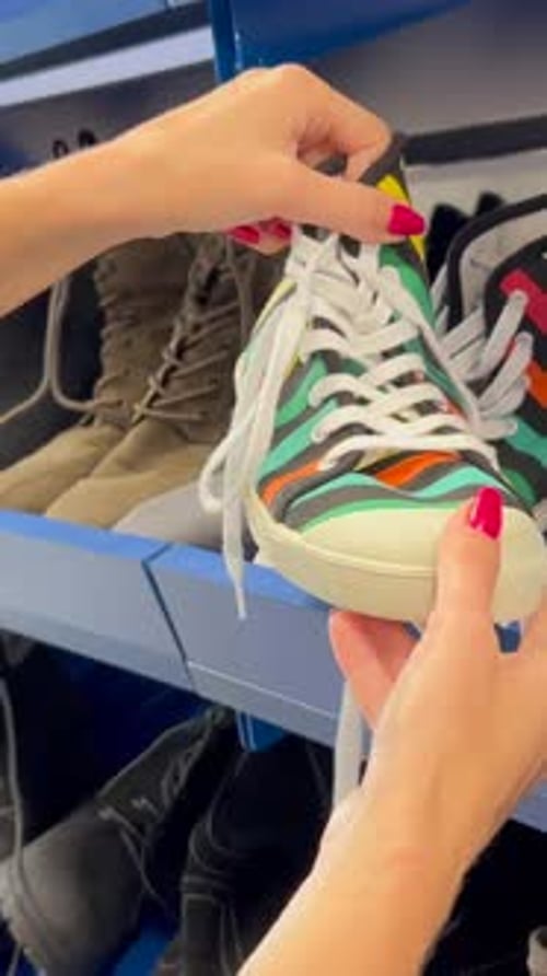 Close Up of Female Hands Looking at Used Shoes on Shelf in Thrift Store Black Friday