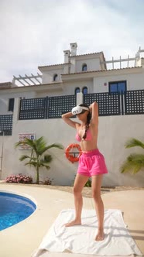 A Woman is Doing Exercise Outdoors By the Pool on a Sunny Day While Wearing a VR Headset