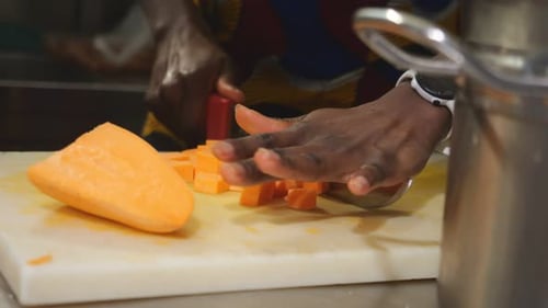 Woman chef cutting yam into concasse cubes for traditional recipe in slow motion