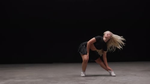 Alluring Young Woman Dancing in Studio Against Black Background